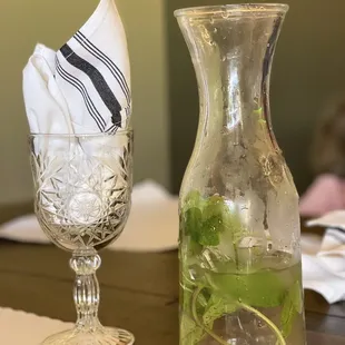 a glass of water and a pitcher of water on a table