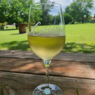 a glass of white wine on a picnic table