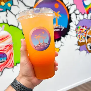 a hand holding a glass of orange juice