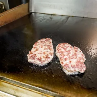 two steaks cooking on a grill
