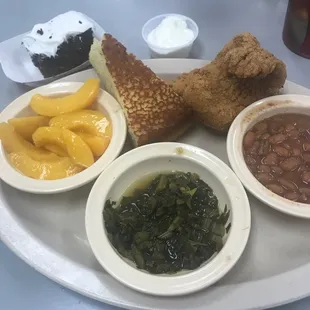Fried catfish, pinto beans, turnip greens, sliced peaches, cornbread, and cake.