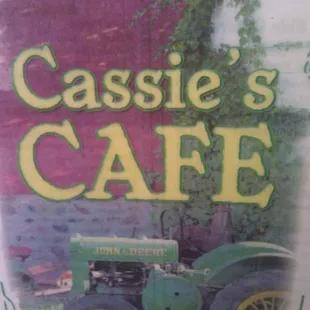 a green tractor in front of a red barn