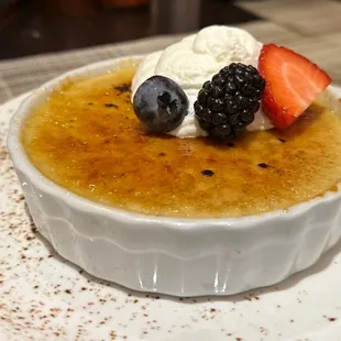 a bowl of creme with berries and whipped cream