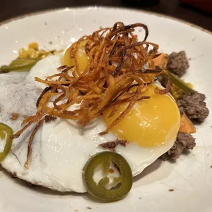 a plate of food with a fried egg and jalapenos