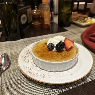 a bowl of creme with berries and whipped cream