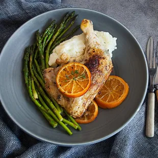 a plate of food with asparagus and orange slices