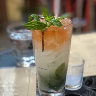 a glass of rum with a mint leaf garnish