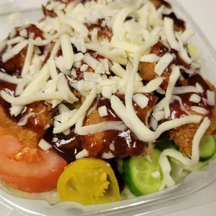 a clear plastic container containing a salad
