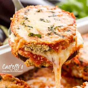 a close up of a piece of lasagna being lifted from a casserole dish