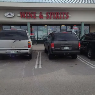 two cars parked in front of a wine and spirits store