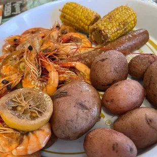 a plate of shrimp, potatoes, and corn