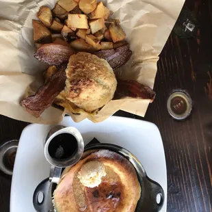 a pancake with a side of potatoes and a biscuit