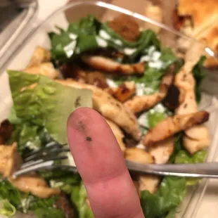 a hand holding a fork in front of a salad