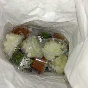 A bag full of onions, cilantro and two other sauces