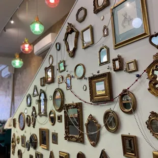a wall full of frames and mirrors