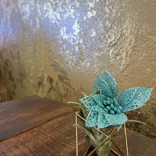 a blue flower in a gold geometric vase