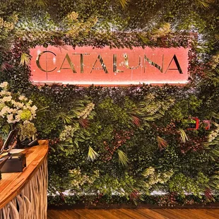 cataluna signage in front of a wall of plants
