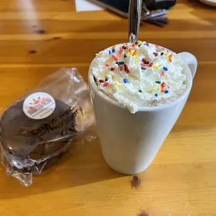 Hot chocolate with marshmallows, whipped cream and sprinkles, and a gluten free vegan double chocolate cookie sandwich