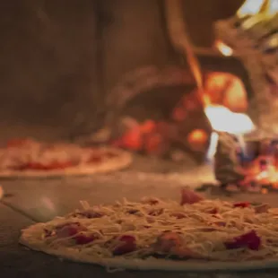ows two pizzas being cooked in a brick oven