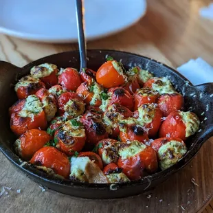 ows a skillet with tomatoes and cheese