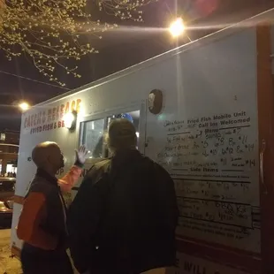 ows a man and a woman standing in front of a food truck