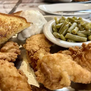 Chicken strips, green beans, mashed potatoes with pepper gravy, garlic bread.