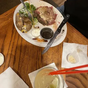 Prime rib with baked potato and shrimp skewers