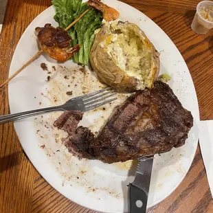 Ribeye with baked potato and shrimp skewers.