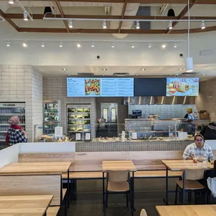 the interior of a restaurant with wooden tables and benches