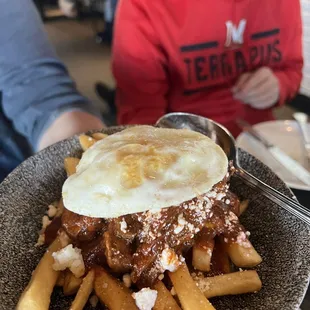 a plate of french fries with a fried egg on top