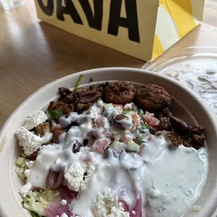 Mixed grains and greens bowl with chicken and half falafel and tzatziki and garlic dressing