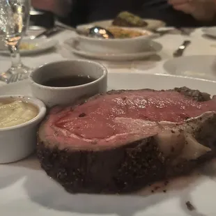 a large piece of meat on a plate with dipping sauces
