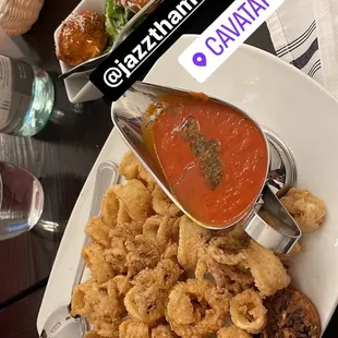 a plate of fried squids and a bowl of tomato sauce
