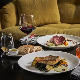 two plates of food and a glass of wine