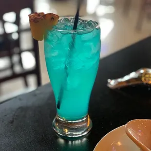 a blue drink with a pineapple garnish