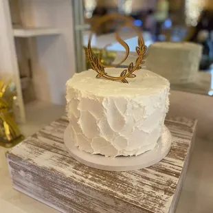 a white frosted cake with a gold crown on top