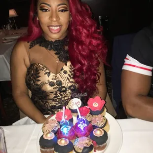a woman sitting at a table with cupcakes