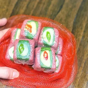 a person holding a plate of sushi rolls