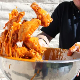 a man holding a bowl of chicken wings
