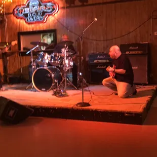 a man kneeling on a stage in front of a band