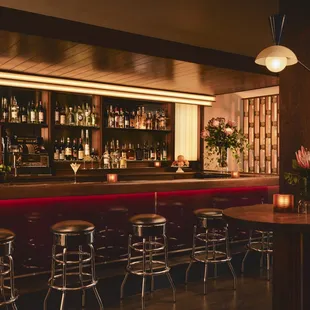 a bar with stools and bottles