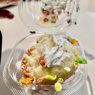 a person holding a plastic container with a cake in it