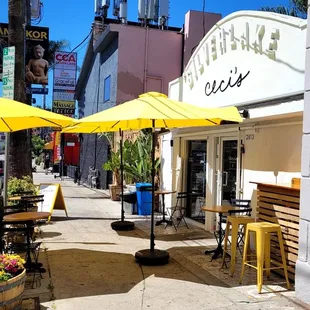 a sidewalk with tables and umbrellas