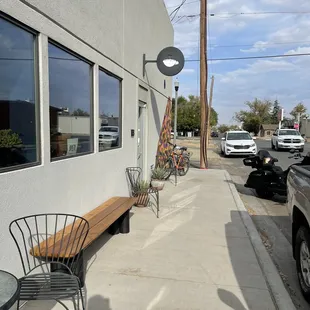 a bench and chairs on a sidewalk