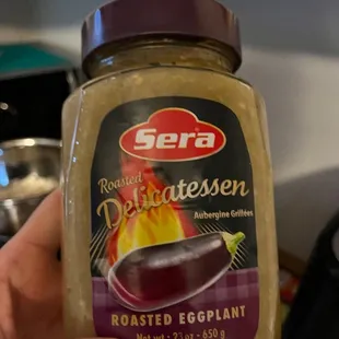 a hand holding a jar of roasted eggplant