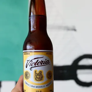 a hand holding a bottle of beer