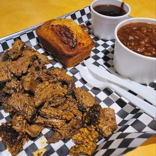 Delicious brisket dinner, corn bread, beans with tasty mild BBQ on the side.