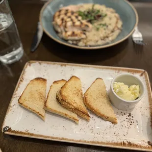 In the foreground- gluten free toast with salted butter. In the background- mushroom risotto with chicken.