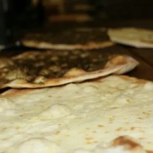 three flatbreads on a wooden table
