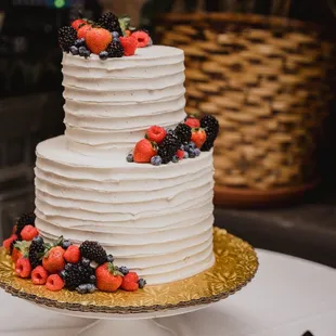 a white wedding cake with berries on top